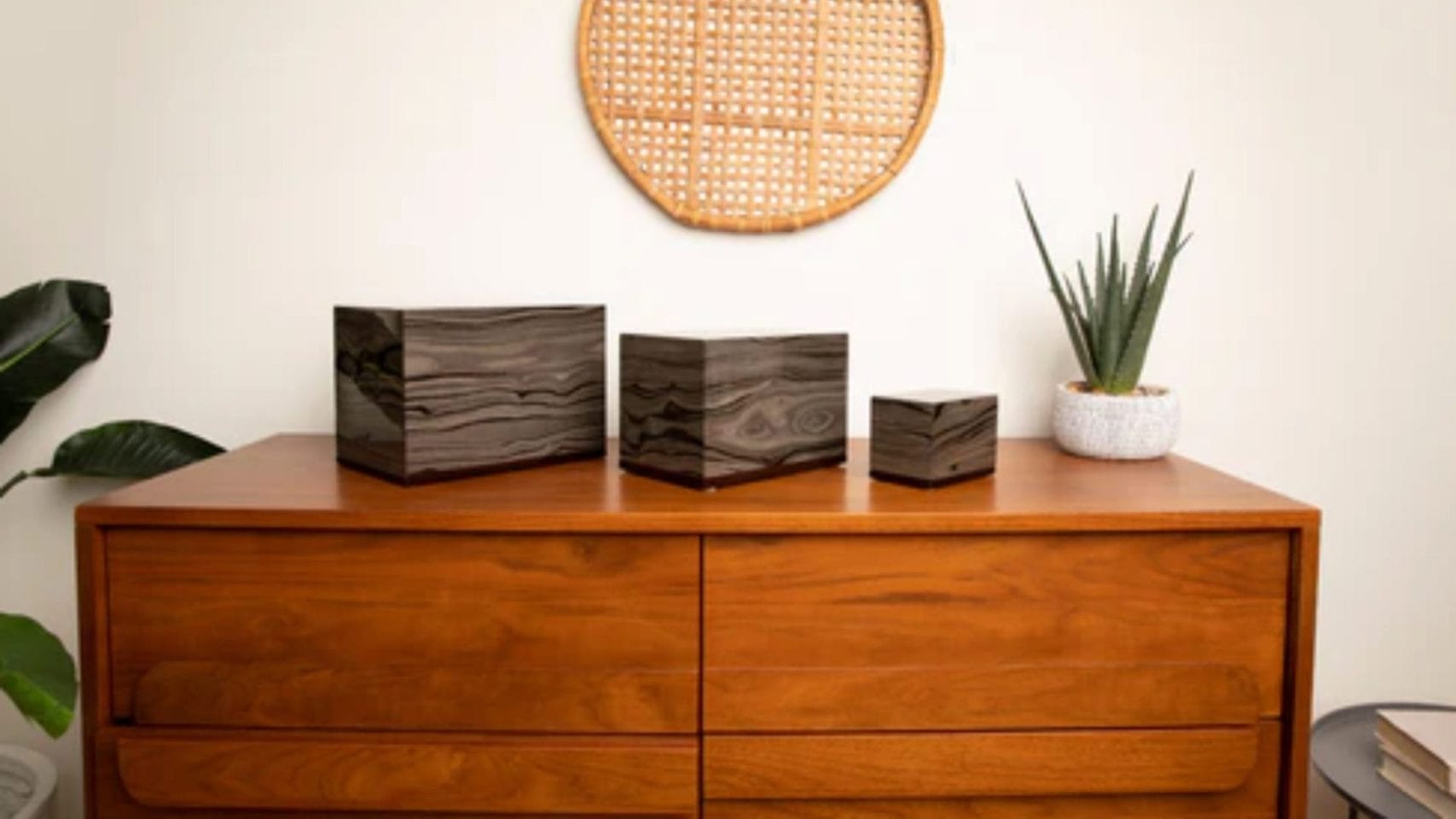 Three wooden urns in different sizes displayed on a dresser.