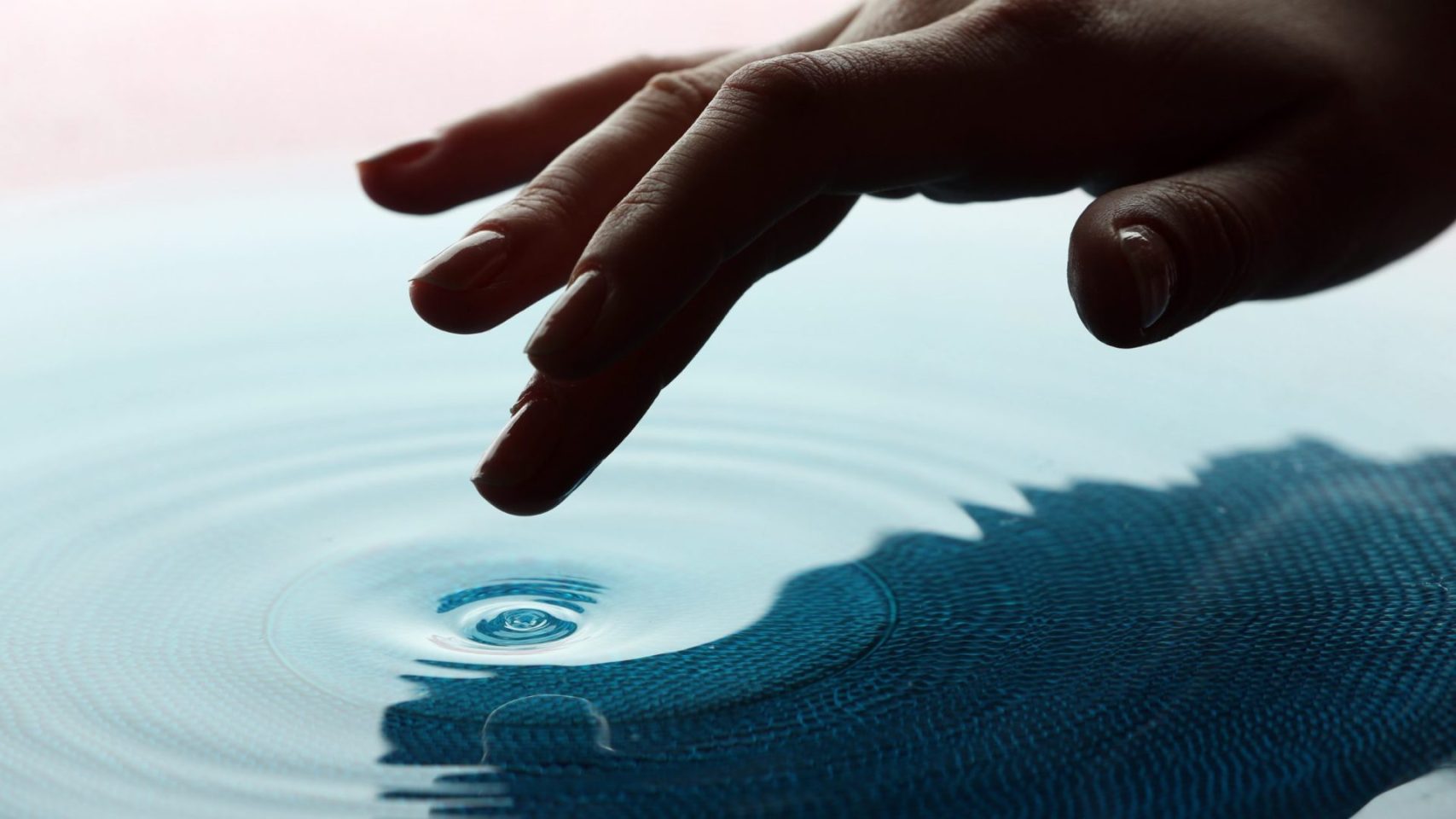 A gentle hand touching water, symbolizing remembrance and care