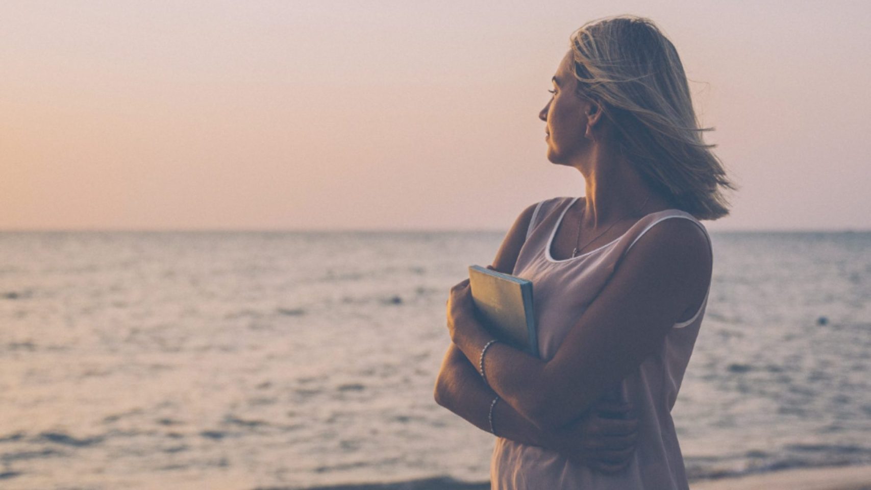 Woman holding a notebook by the water, reflecting on Houston cremation package options