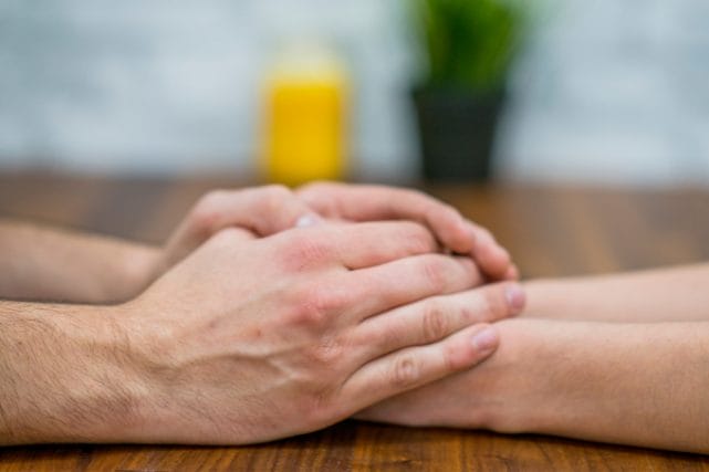 Hands gently held across a table, representing compassionate cremation support for Houston families.