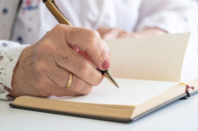 Person writing in a notebook while planning cremation costs in The Woodlands, TX.