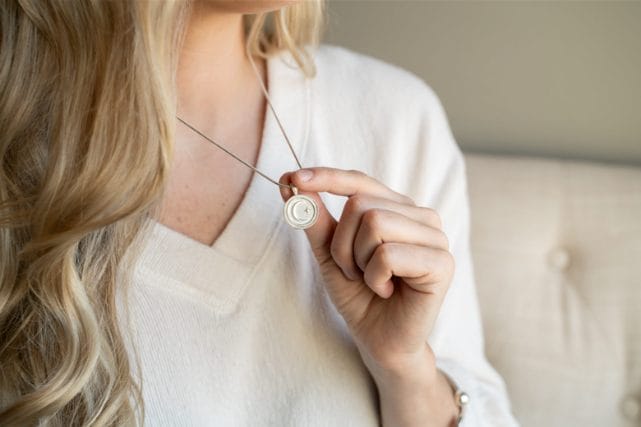 woman holding cremation necklace pendant with ashes memorial jewelry