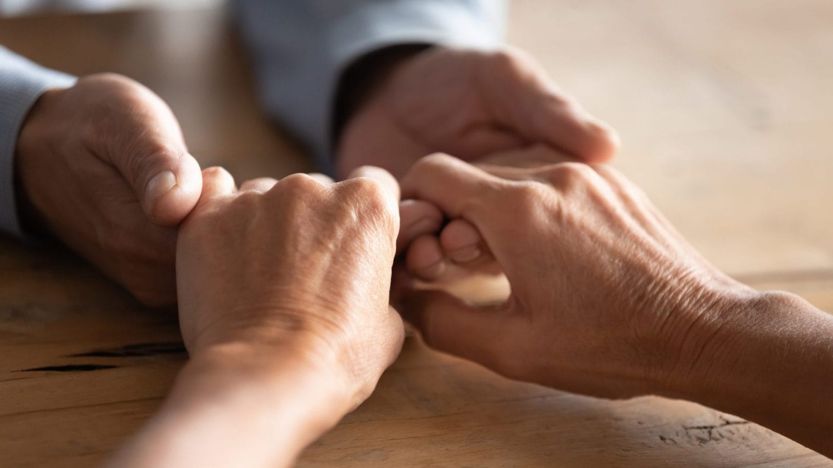 Hands held in comfort during a difficult family conversation.