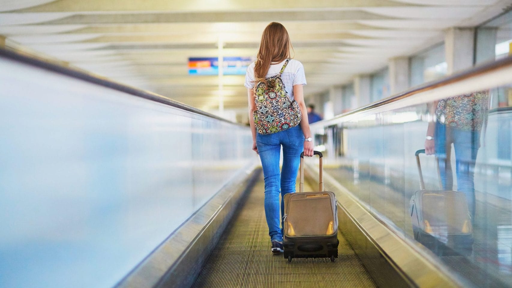 Traveler walking through an airport with a carry-on bag for families who travel with ashes on a plane.