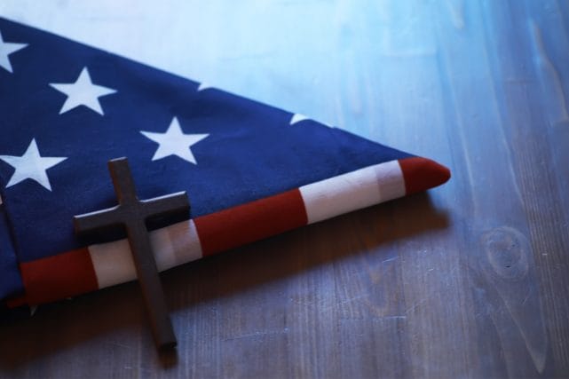 Folded American flag and cross representing veteran cremation discounts and memorial honors