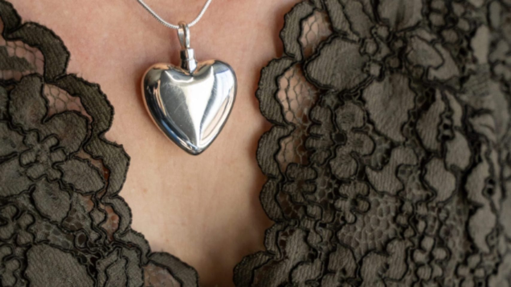 Silver heart cremation necklace worn as a personal memorial keepsake.