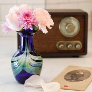 Living Glass Keepsake in a blue with green color on a table next to a radio and old image.
