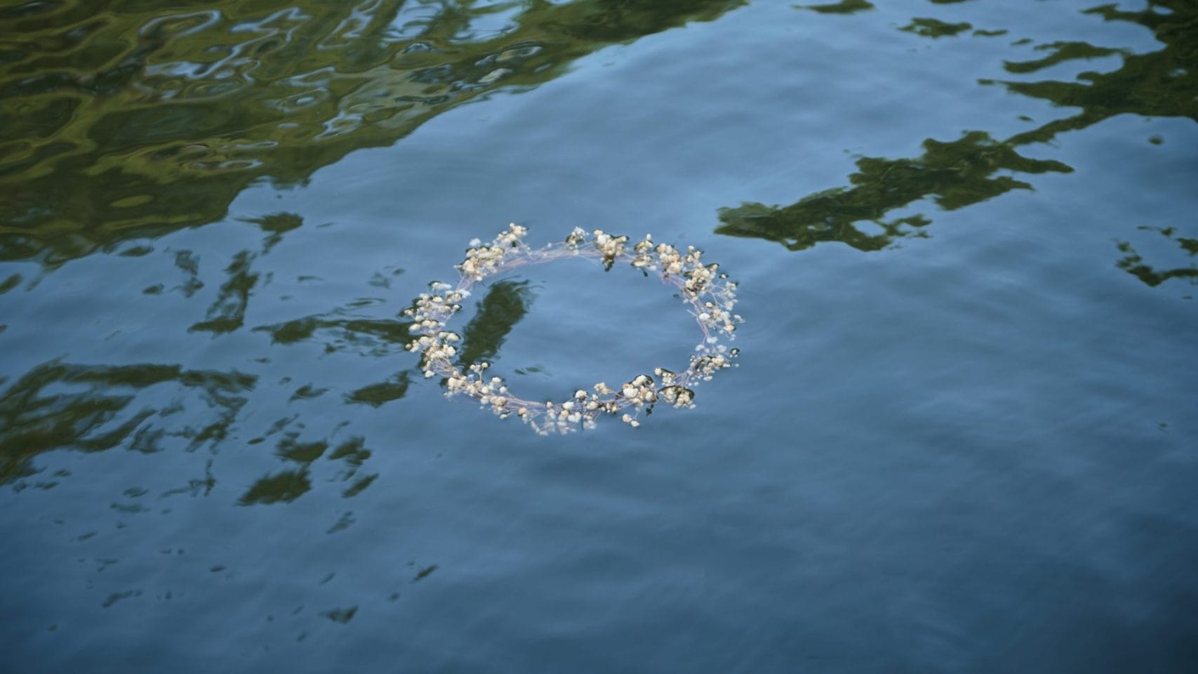 Flower wreath floating on water for a memorial after direct cremation in Texas City, Texas.