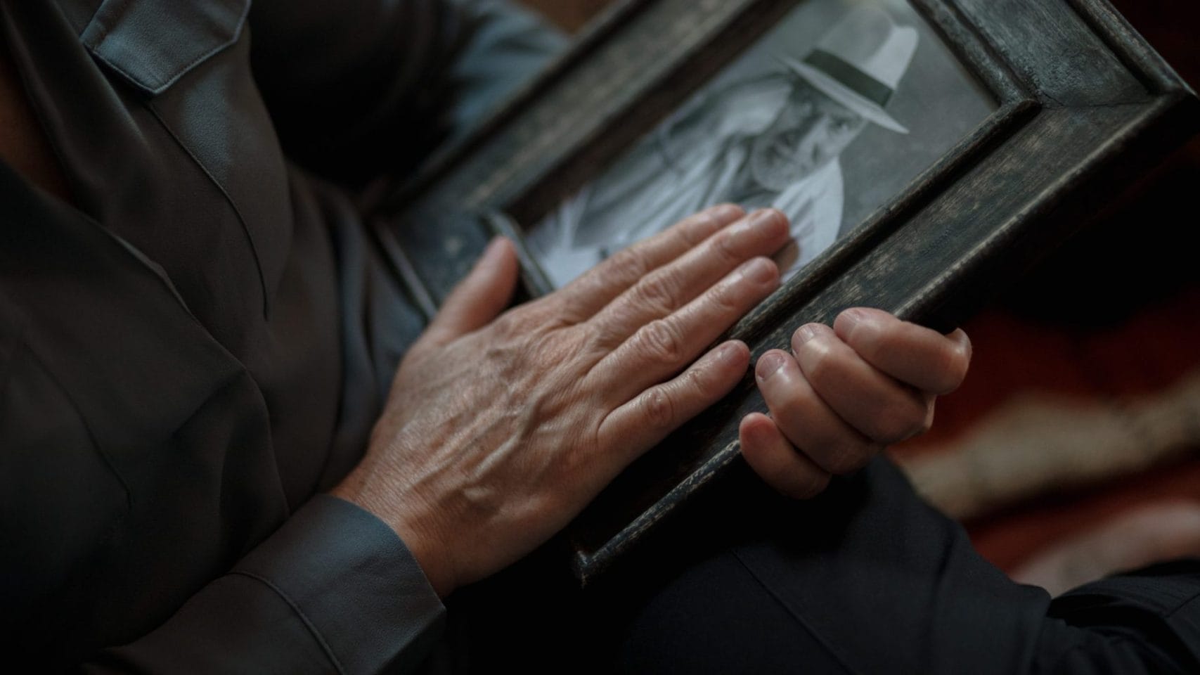 Person holding a framed photo while remembering a loved one.