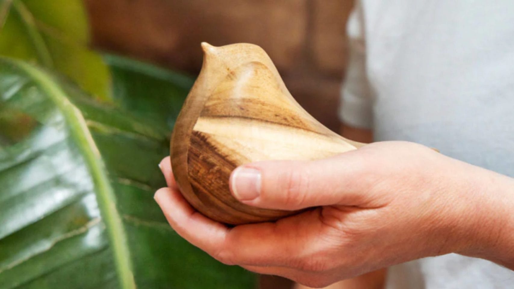 Small wooden bird keepsake held in someone’s hand.