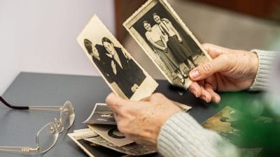 Hands holding old family photos while remembering a loved one after cremation
