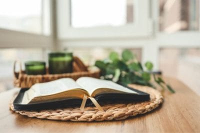 Open Bible on a wooden table in soft natural light for an article about what the Bible says about cremation.