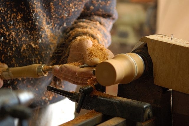Craftsman turning a wooden cremation urn on a lathe.