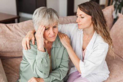 A loving adult daughter conversing with her sad elderly mother