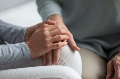 Seated on couch grown up daughter holding touching mothers hand