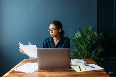 Serious businesswoman sitting by a desk and holds documents
