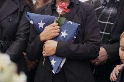 Funeral, graveyard and woman with American flag for veteran for respect