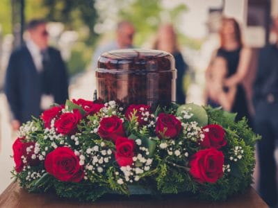 Funerary urn with ashes of dead and flowers at funeral